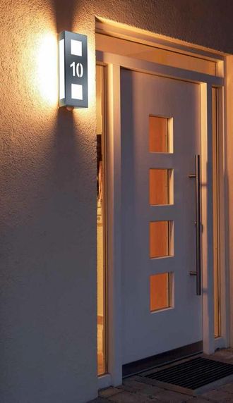 Beleuchtete Hausnummer neben Haustür bei Nacht
